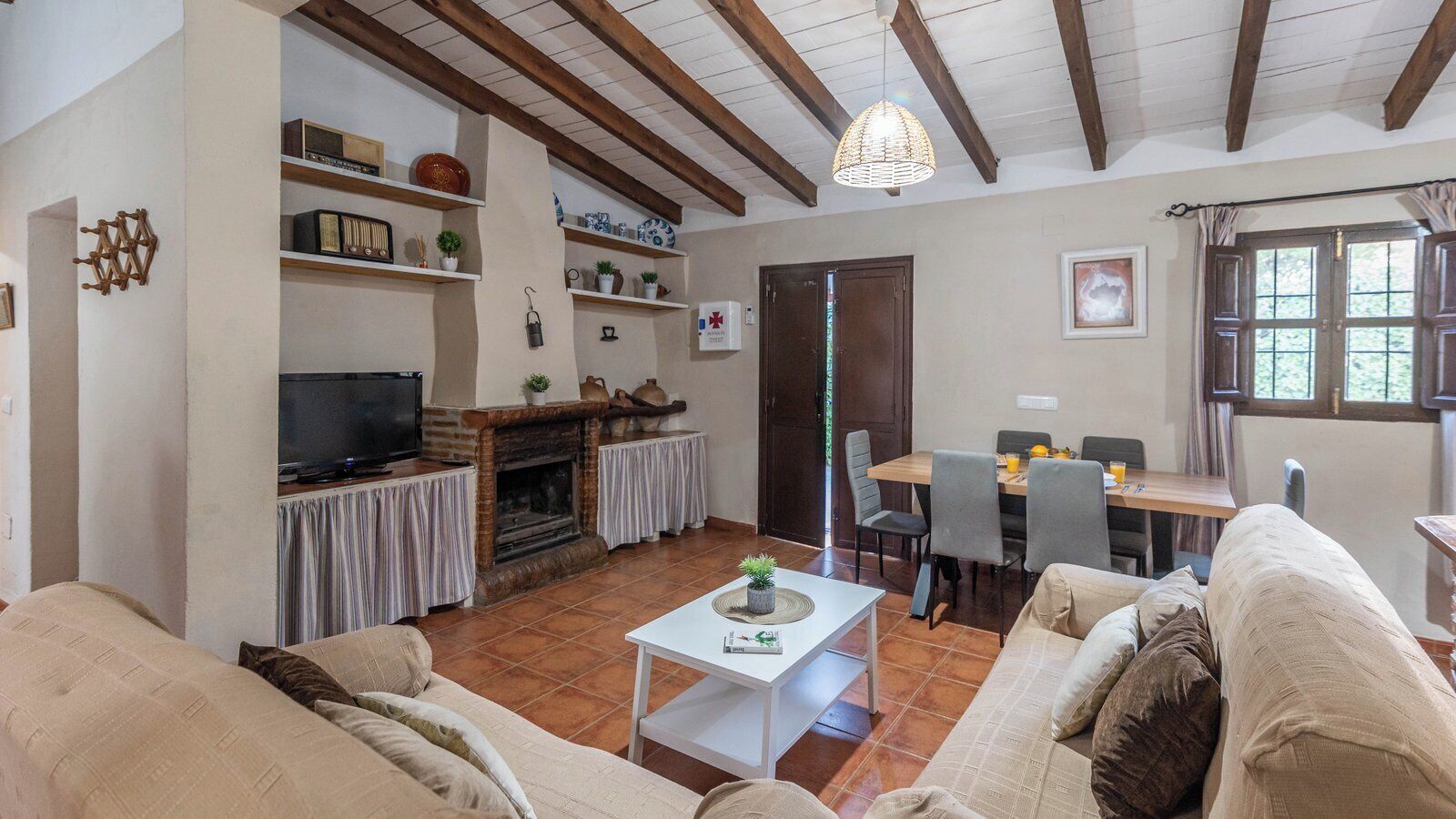 Una sala de estar acogedora con chimenea, televisor y comedor con mesa y sillas.
