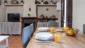 Ein Essbereich mit einem Holztisch, gedeckt für das Frühstück, inklusive Tellern, Gläsern mit Orangensaft und einer Obstschale.
