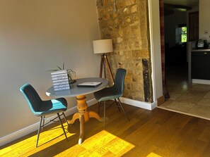 A dining area with a round table, two chairs, a lamp, and a guest book.