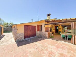 A patio with a stone floor, a wooden door, and a barbecue area with a table and chairs.