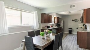 A modern kitchen with wooden cabinets, a dining table with chairs, and a small island with a sink. - Spacious retreat near Dallas for group stays (Garland)