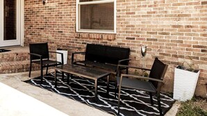 A patio with a brick wall, a window, and a black and white patterned rug. - Spacious retreat near Dallas for group stays (Garland)