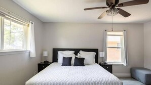 A bedroom with a large bed, two bedside tables, a ceiling fan, and two windows. - Spacious retreat near Dallas for group stays (Garland)