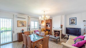A living room with a TV, sofa, and dining area.