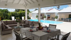 Un espace extérieur abrité comprenant une piscine, une table à manger pour quatre personnes et un canapé.