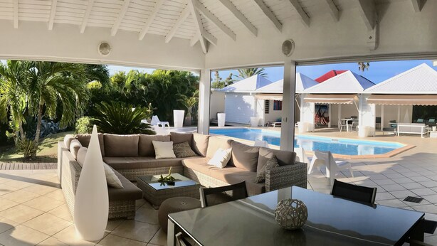 Un espace extérieur aménagé, abrité et doté d’une piscine, d’un canapé et d’une table.