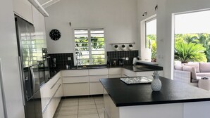 Une cuisine moderne avec des meubles blancs, un plan de travail noir et une grande fenêtre.
