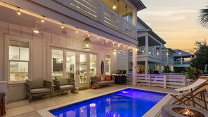 A pool area with lounge chairs, a barbecue, and a deck overlooking the pool.