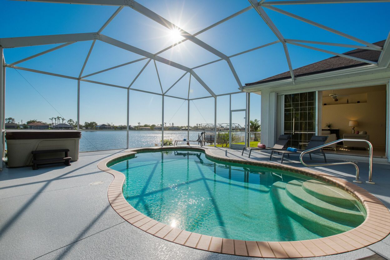 A covered swimming pool with a view of the water and a distant bridge.