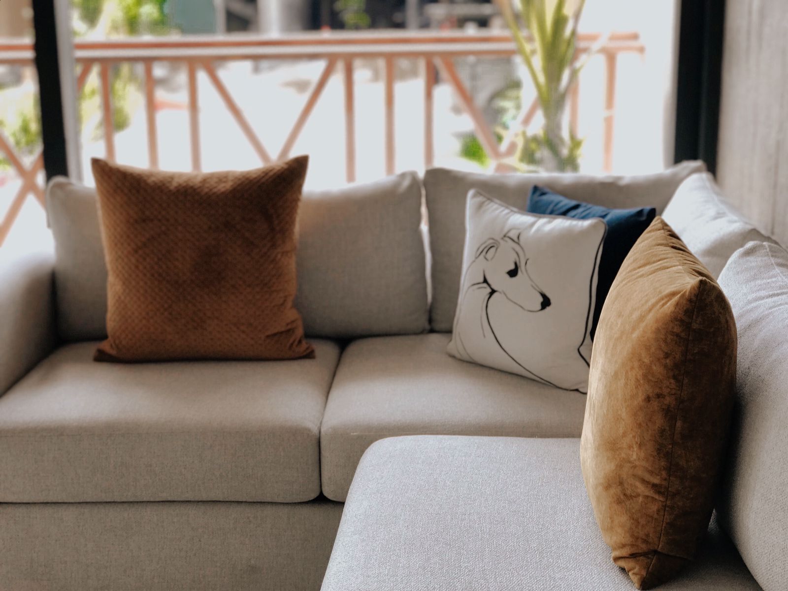 A sectional sofa with three pillows, one of which has a dog design.