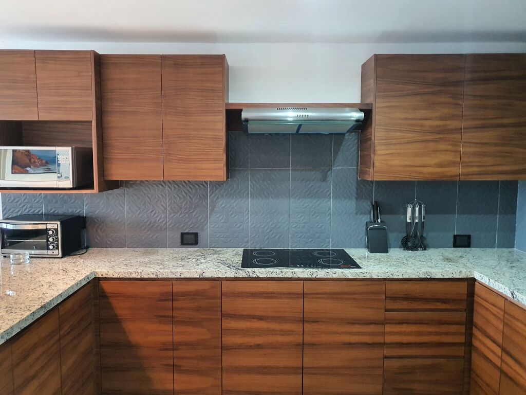 Une cuisine avec des meubles de rangement en bois, un four à micro-ondes, un grille-pain, une cuisinière et un pare-feu.