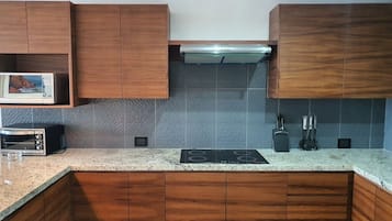 Une cuisine avec des meubles de rangement en bois, un four à micro-ondes, un grille-pain, une cuisinière et un pare-feu.