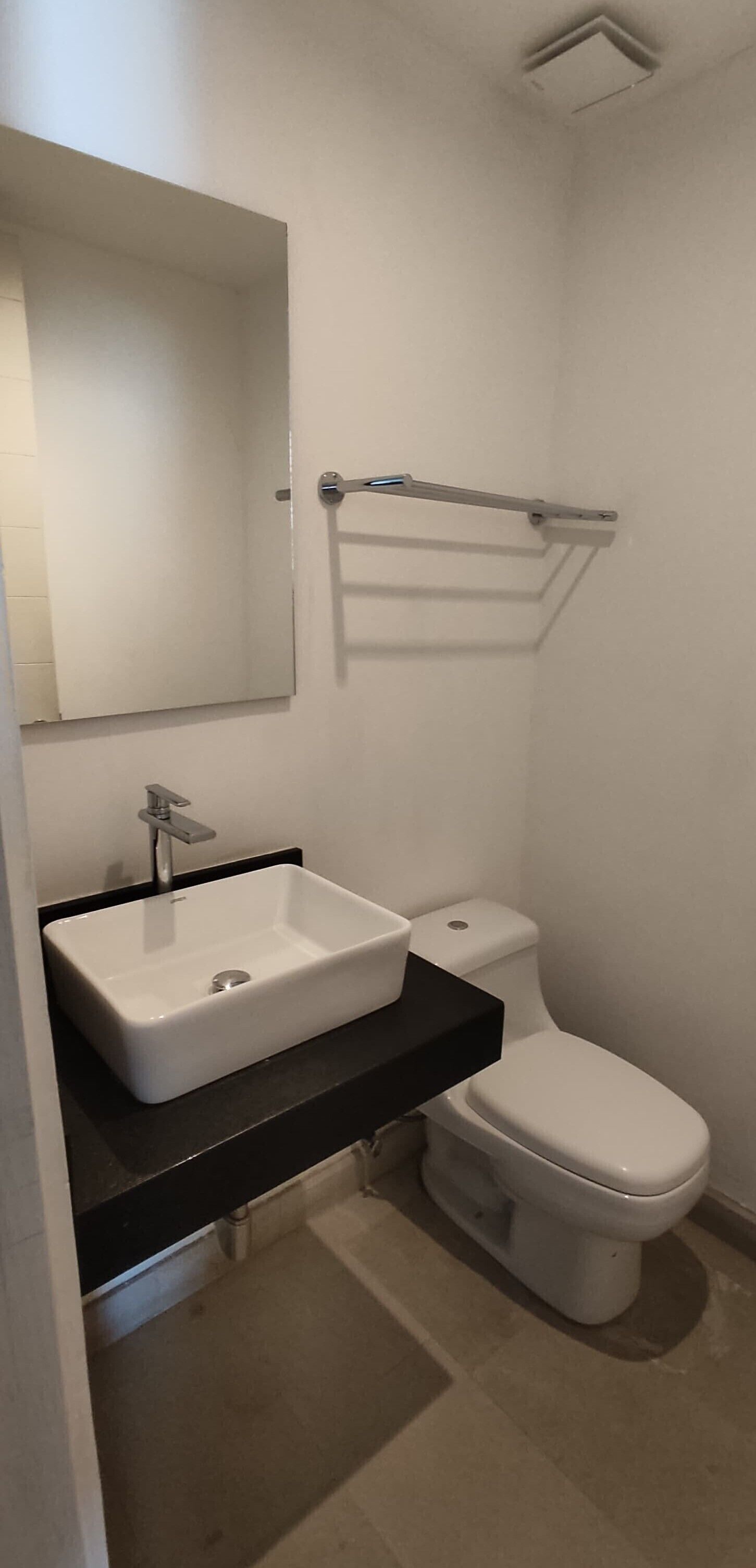 A bathroom with a white sink, a mirror, and a toilet.