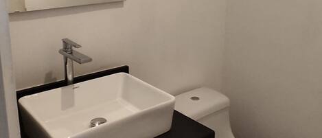 A bathroom with a white sink, a mirror, and a toilet.