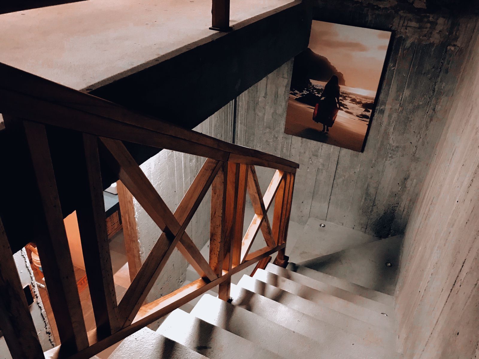 Una escalera con baranda de madera y pared de hormigón.