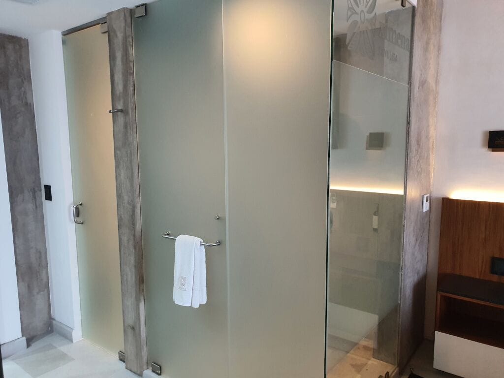 A modern bathroom with a glass shower enclosure, a towel rack, and a wooden vanity.