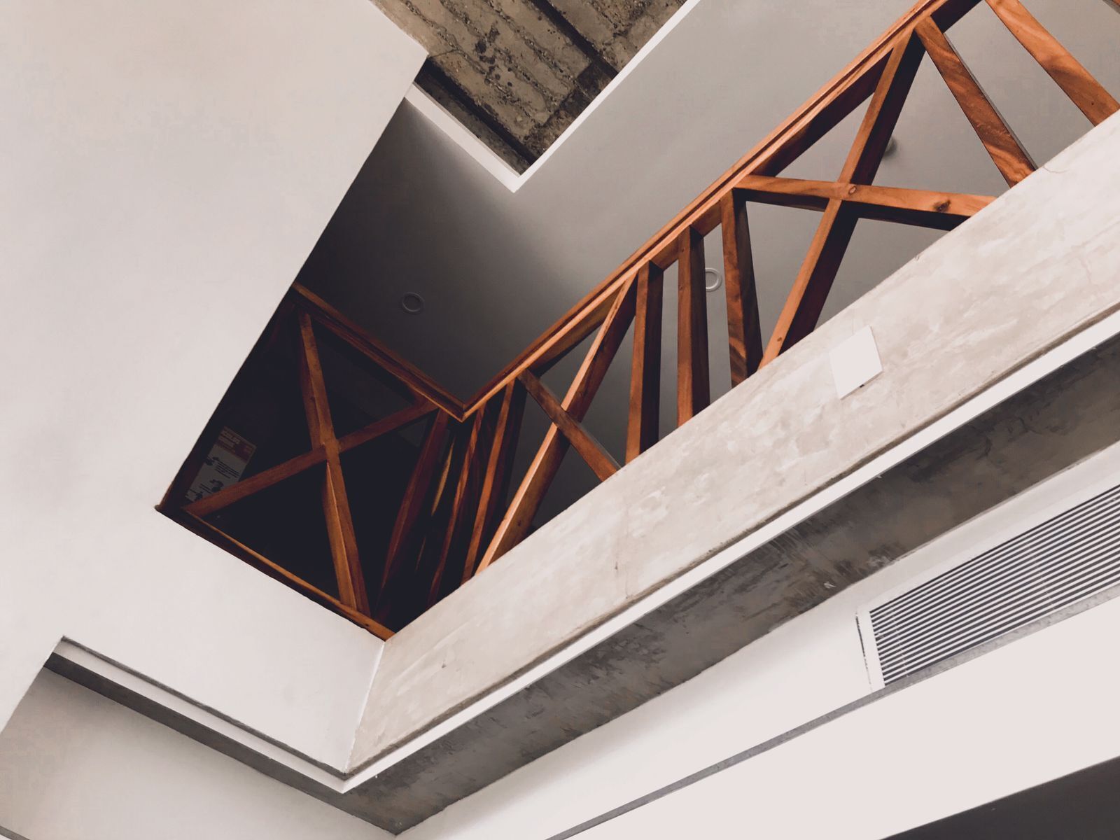 A modern architectural design with a geometric staircase and exposed wooden beams.