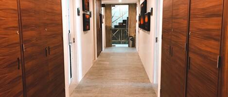 A hallway with wooden paneling, a tiled floor, and framed artwork on the walls.