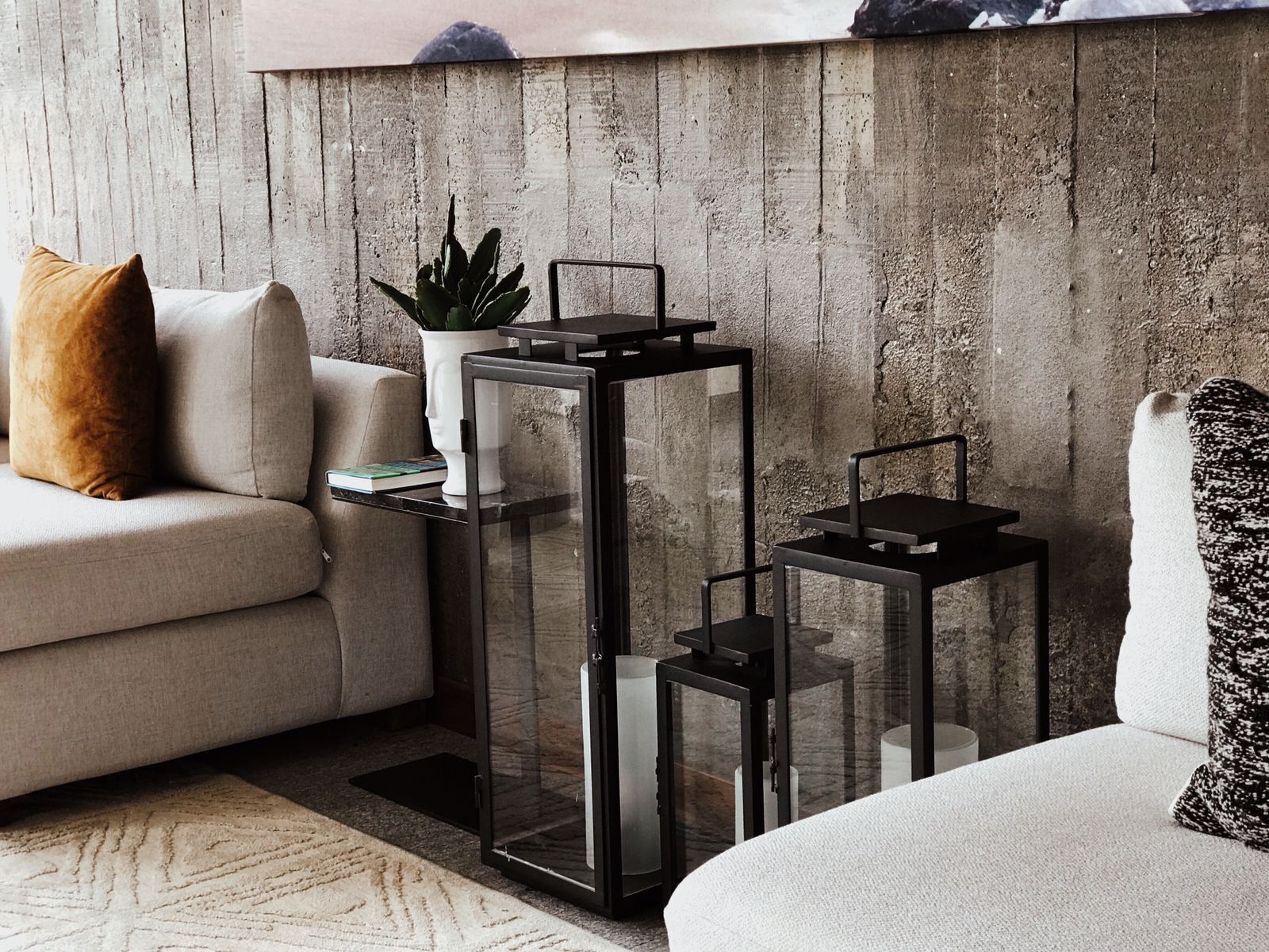 A living room with a sofa, a coffee table, and a glass-top side table with a plant and a book.