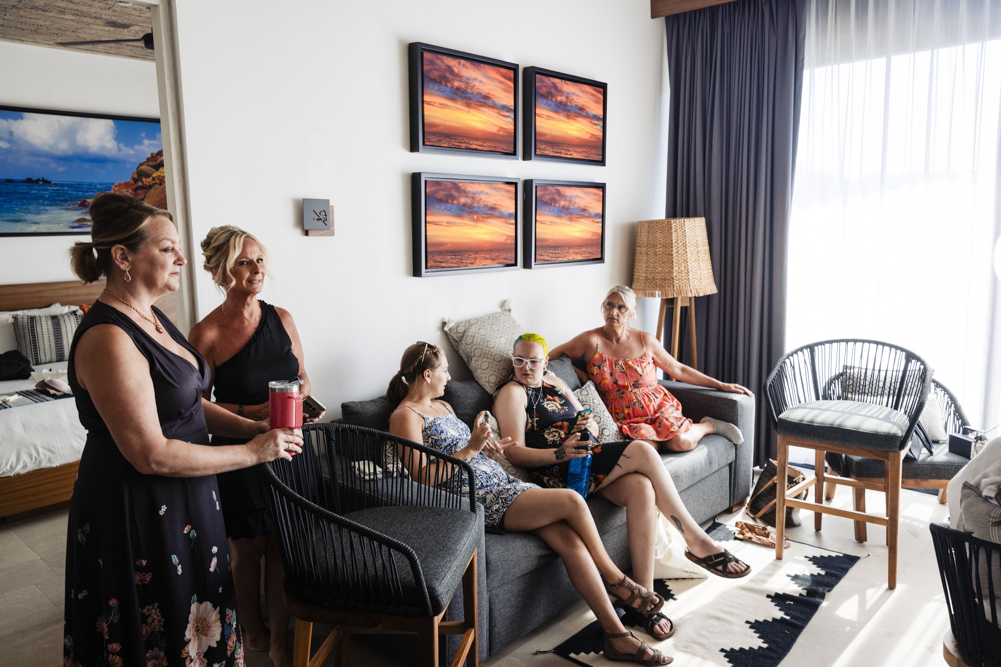 Un salon avec un canapé, des fauteuils et une table basse. Quatre tableaux encadrés ornent le mur.