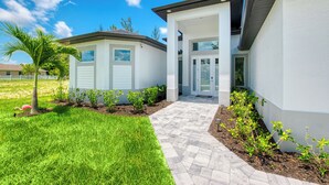 A modern two-story house with a paved driveway and a well-maintained lawn.