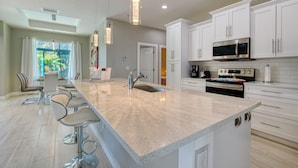 A modern kitchen with a central island, stainless steel appliances, and white cabinetry.