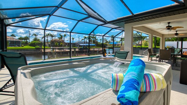 A hot tub with a glass enclosure, a pool, and outdoor seating.