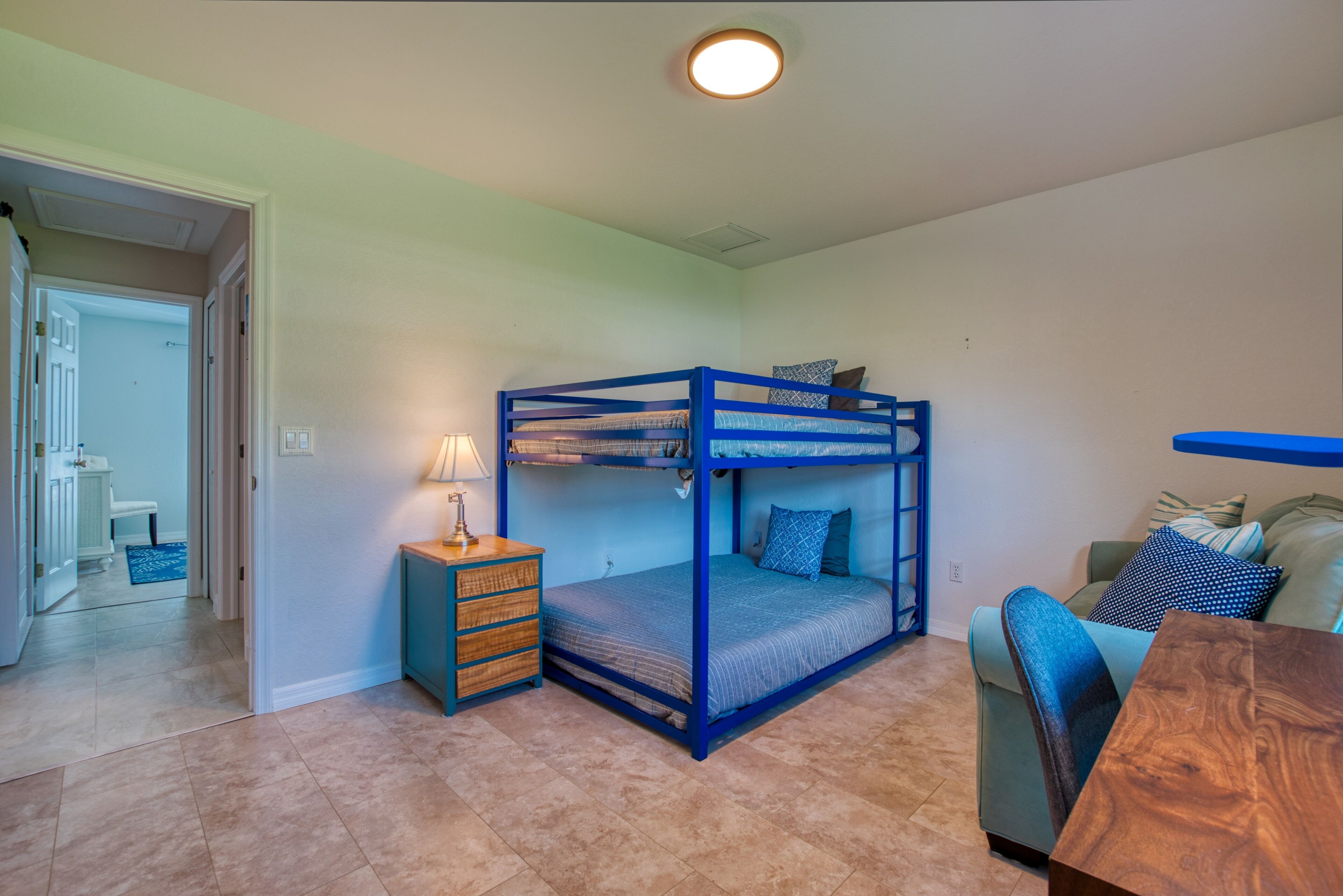 Un dormitorio con una cama litera, una mesita de noche con lámpara, un sofá y una mesa de centro de madera.