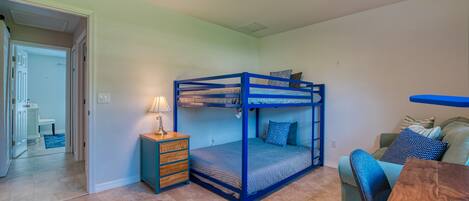 Un dormitorio con una cama litera, una mesita de noche con lámpara, un sofá y una mesa de centro de madera.