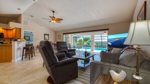 A spacious living room with a view of a pool, a kitchen area, and a dining space.