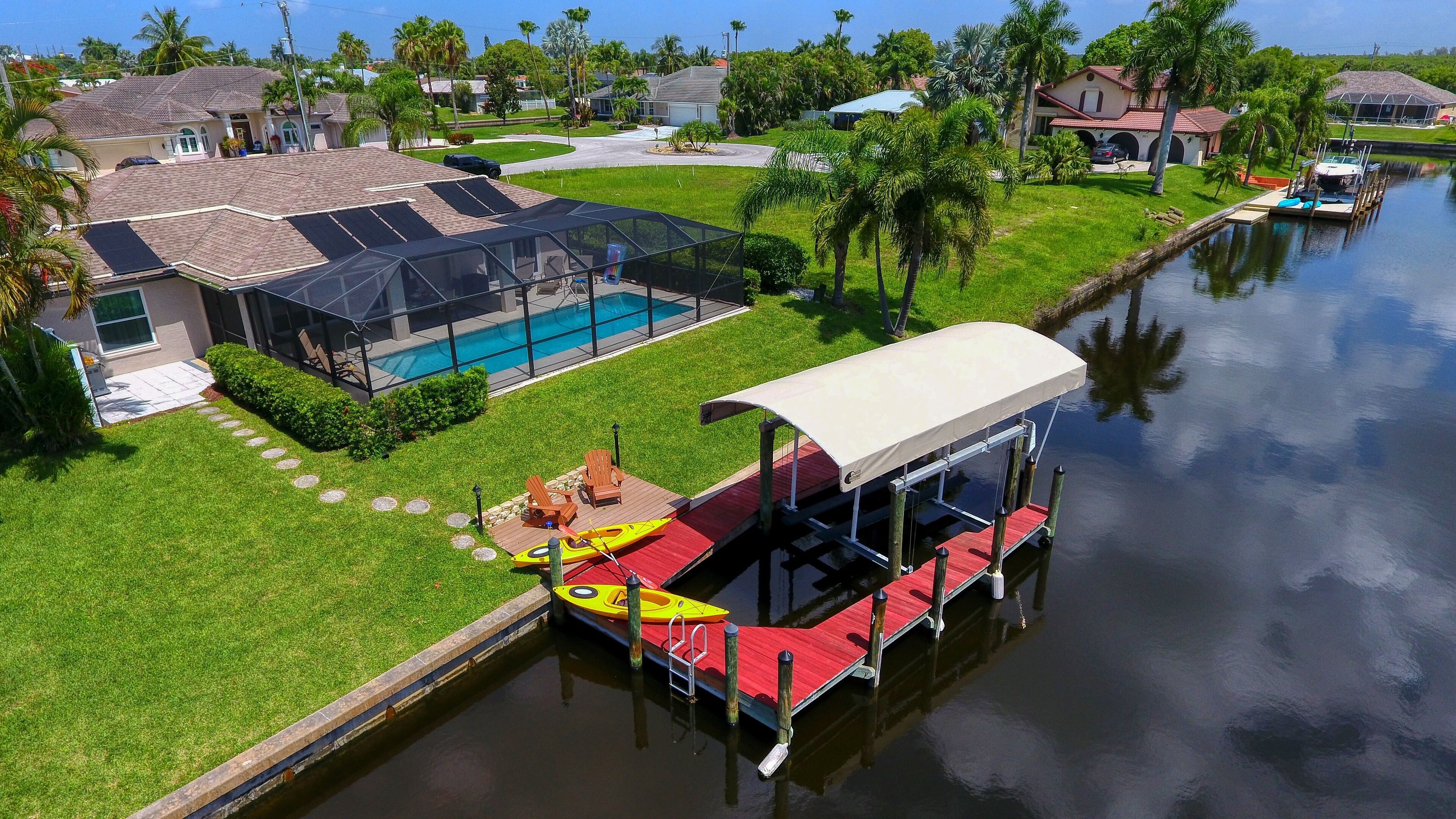 A residential property with a swimming pool, a covered dock, and a canal.