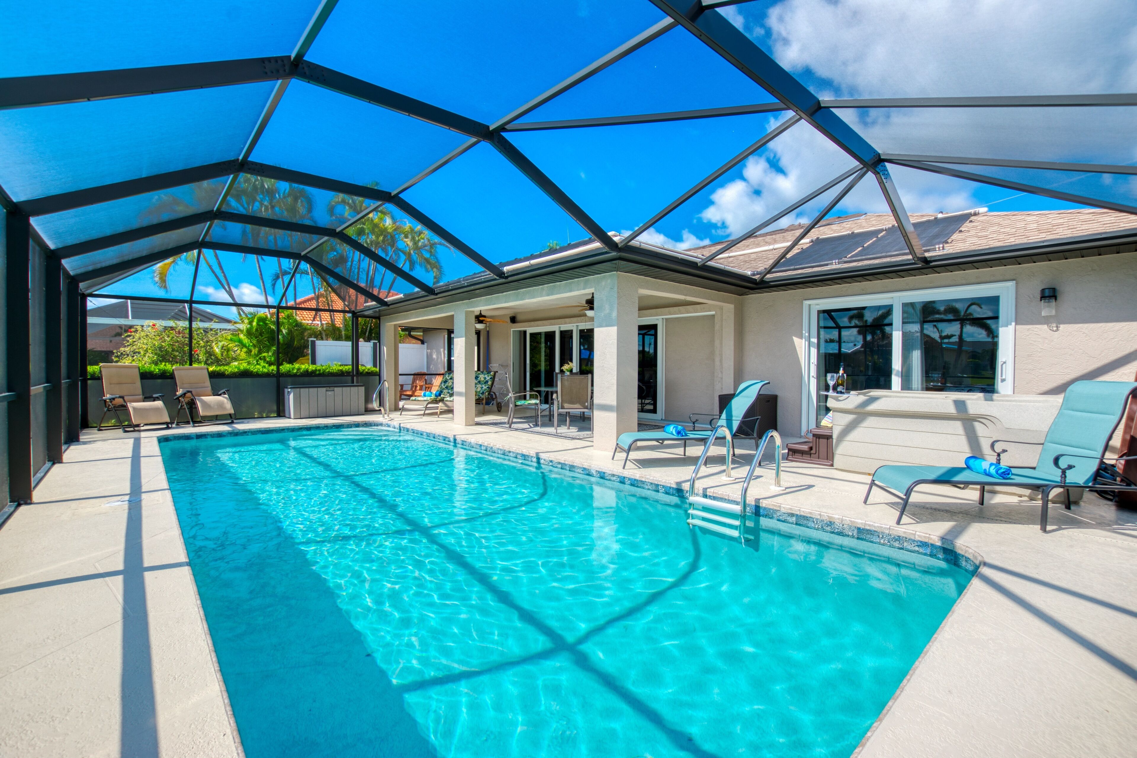 Ein Schwimmbad mit Glasdach, umgeben von Liegestühlen und einer überdachten Terrasse.