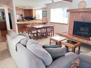 A living room with a sofa, coffee table, fireplace, and kitchen area in the background. - 2620 Merlyn Ave.   Lodge Hill (Cambria)