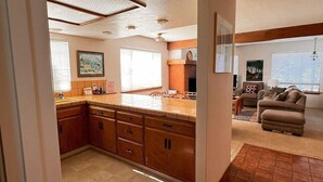 A kitchen with wooden cabinets, a tiled backsplash, and a dining area with a sofa and a coffee table.