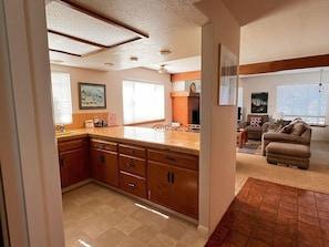 A kitchen with wooden cabinets, a tiled backsplash, and a dining area with a sofa and a coffee table. - 2620 Merlyn Ave. Lodge Hill (Cambria)