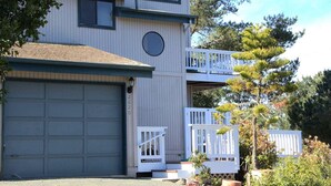 A two-story building with a garage, a balcony, and a small porch.