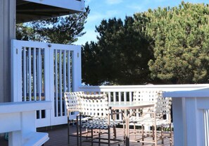 Eine Terrasse mit weißen Geländern, einem Tisch und Stühlen.