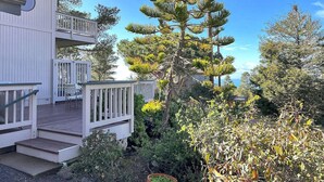A two-story building with a balcony, surrounded by dense vegetation and a clear sky.