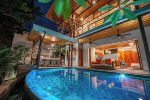 A modern house with a swimming pool, a dining area, and a living room with a sofa.