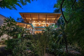 A modern building with a flat roof, surrounded by dense tropical vegetation.