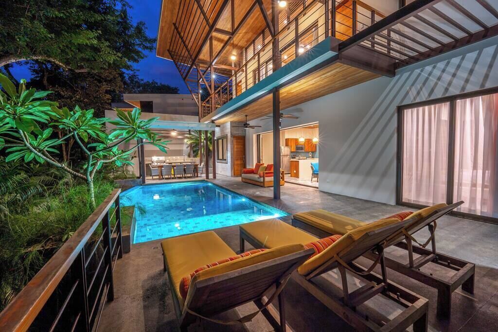 A modern house with a swimming pool, outdoor seating, and a visible kitchen area.