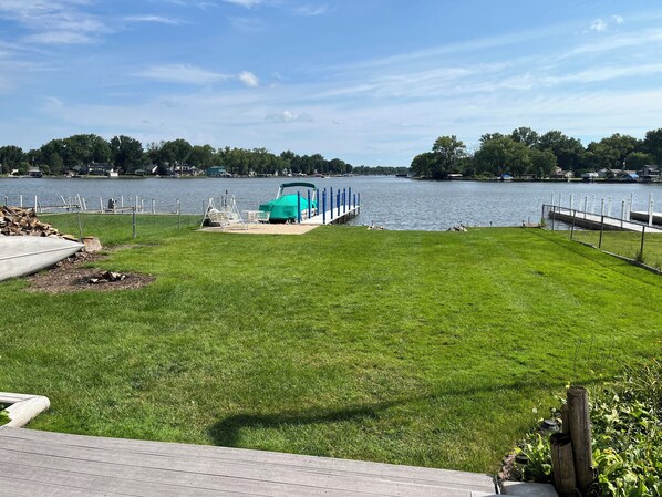 A grassy deck with a view of a lake and a dock.