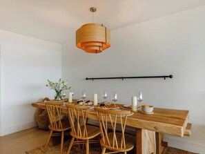 Un coin repas avec une table en bois, quatre chaises et un luminaire suspendu.