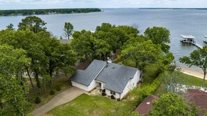 Una casa con techo inclinado, rodeada de árboles y un lago.