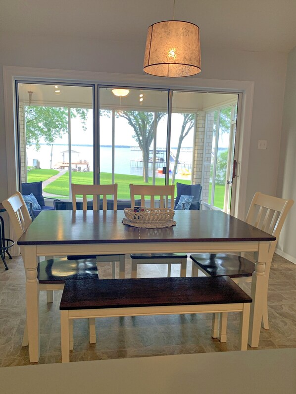 A dining area with a large table, chairs, and a view of a lake through glass doors.