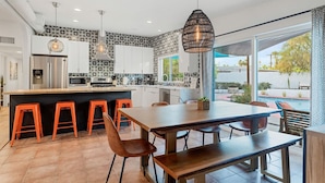 Una cocina moderna con una isla central, taburetes de bar y un comedor con vistas al exterior.
