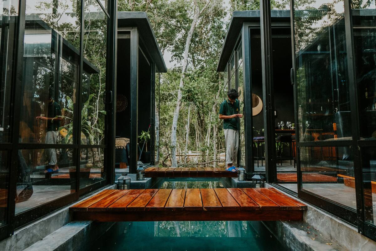 A modern, glass-walled structure with a wooden deck and a central water feature.