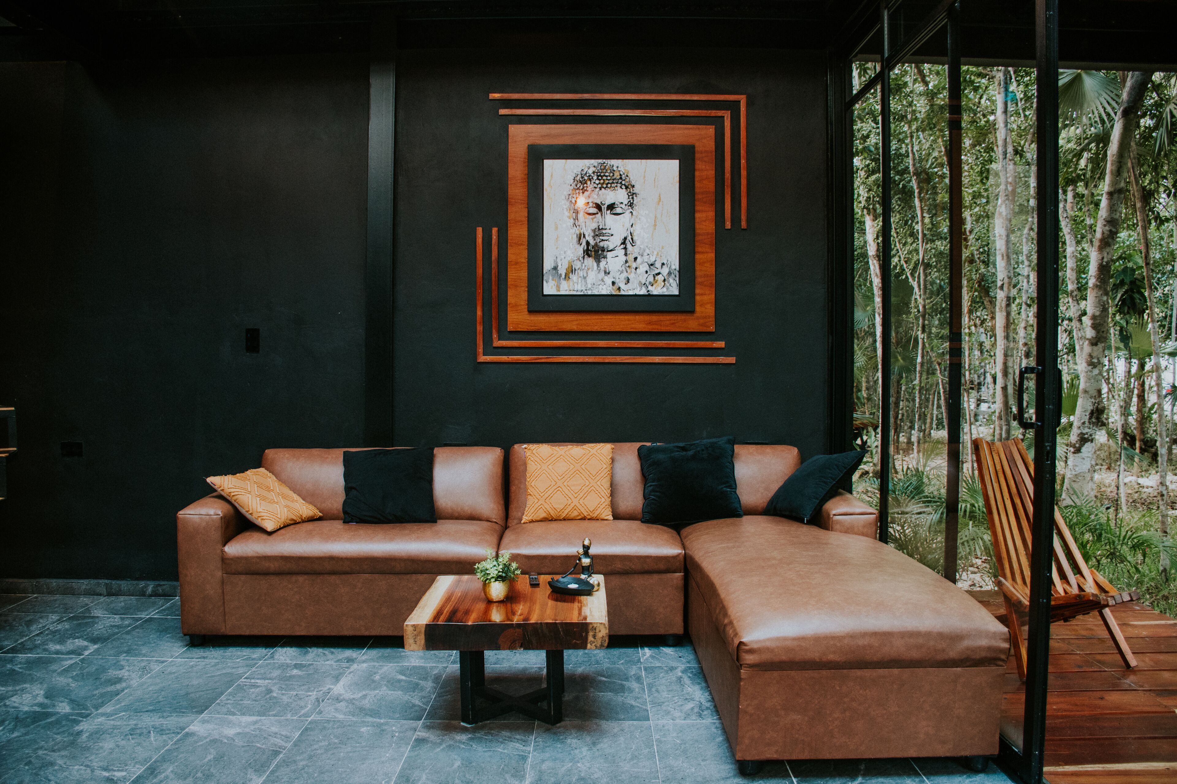 Un salon moderne avec un canapé en cuir marron, une table basse en bois et une grande œuvre d’art encadrée accrochée au mur.