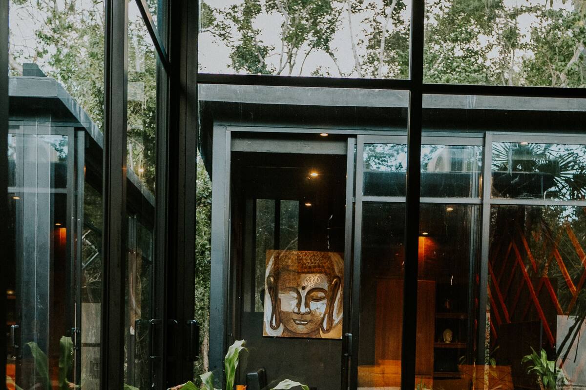 A modern interior with a large glass door leading to a balcony, a bed, and a potted plant.