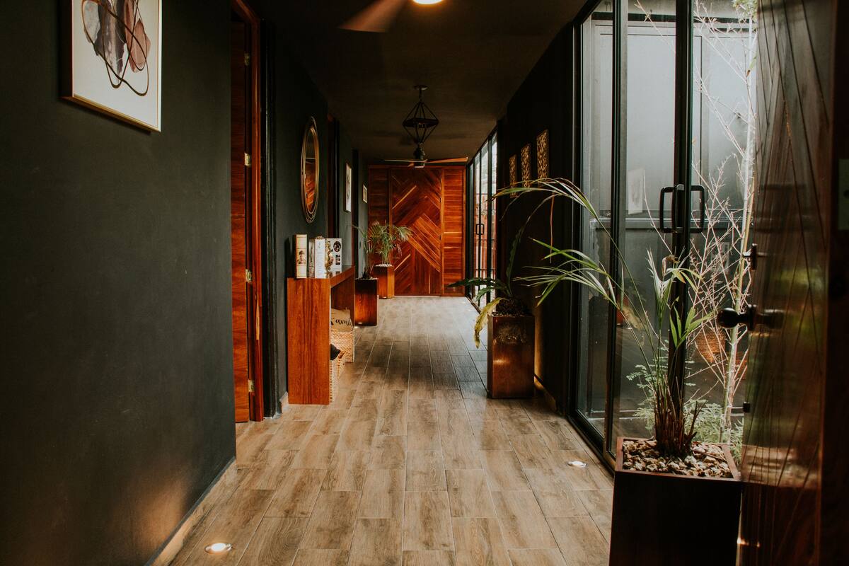 A hallway with wooden flooring, a potted plant, and a framed picture on the wall.